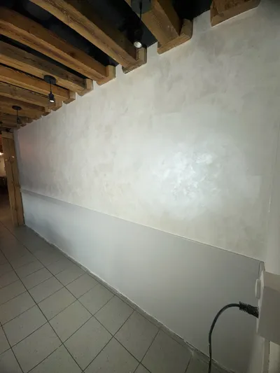 Hochwertig verputzte Stucco-Wand mit edlem Glanzfinish unter einer Decke aus rustikalen Holzbalken – professionelle Malerarbeit in Winterthur.