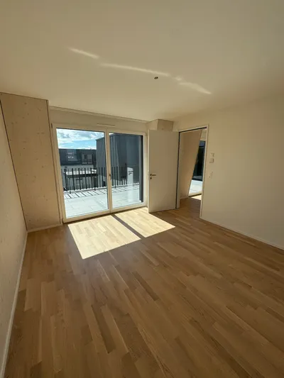 Modernes, helles Schlafzimmer in Winterthur mit Holzverkleidung, Parkettboden und direktem Zugang zum Balkon – frisch gestrichen vom Malerbetrieb in Winterthur.