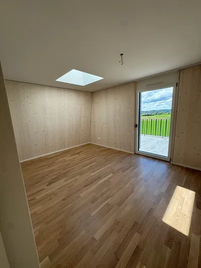 Helles Zimmer in Winterthur mit Holzverkleidung, Dachfenster und Parkettboden – moderne Innenmalerei und hochwertige Ausführung vom Malerbetrieb in Winterthur.